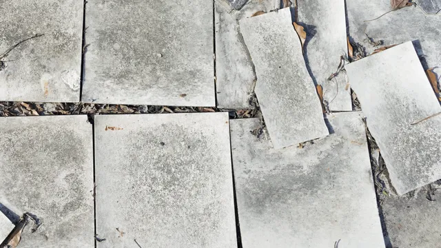 Loose and damaged asbestos-containing vinyl floor tiles, with sections lifted and broken. These tiles and the underlying adhesive should be assessed before removal or disturbance.