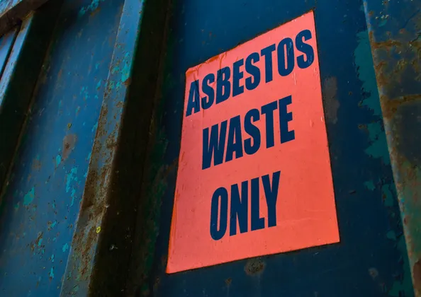 'Asbestos waste only' warning sign on the side of a licensed asbestos waste skip