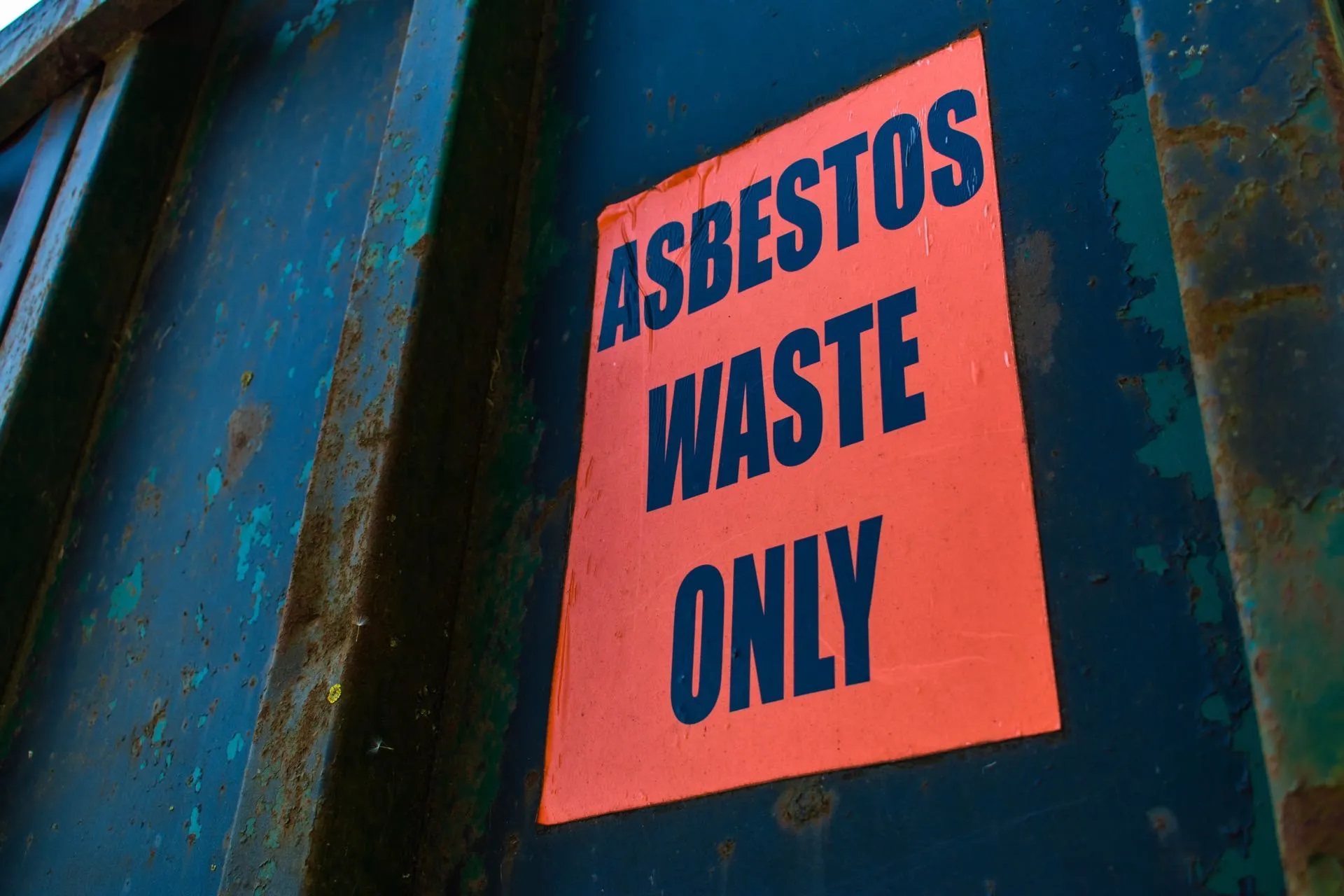 'Asbestos waste only' warning sign on the side of a licensed asbestos waste skip