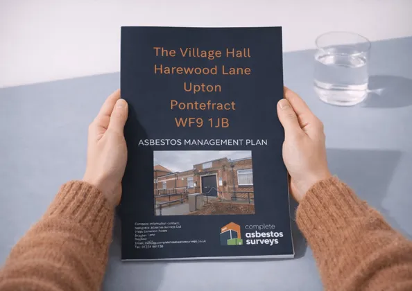Hands holding a printed Complete Asbestos Surveys asbestos management plan for a village hall