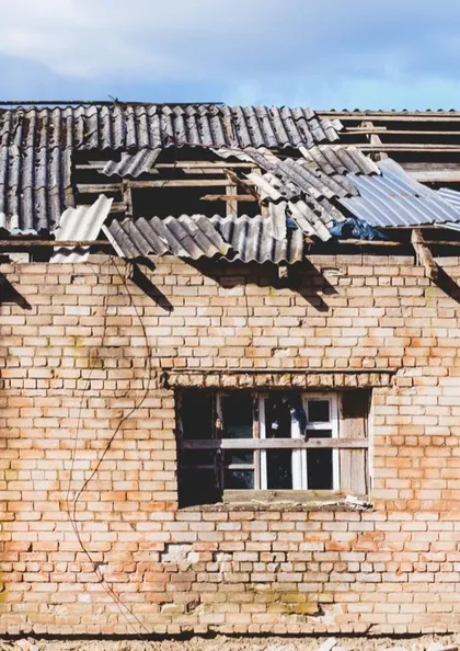 Derelict brick building with a damaged corrugated asbestos cement roof awaiting removal