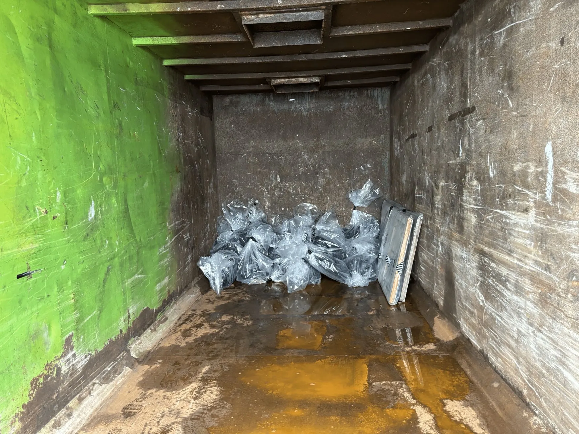 Double-bagged asbestos waste stacked inside a skip, ready for transport to an authorised facility