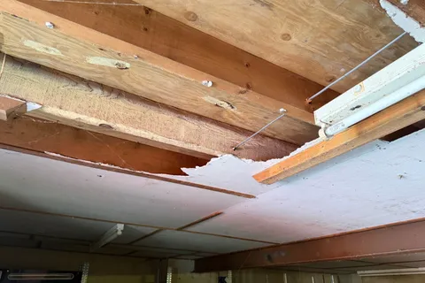 Close-up of damaged asbestos insulating board (AIB) identified within the garage ceiling of a York farmhouse, requiring prompt remedial action.