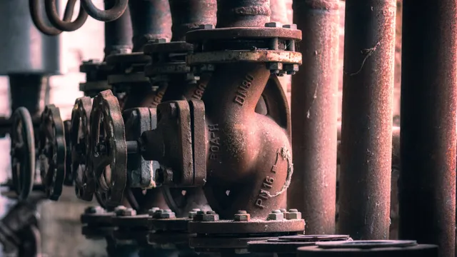 Industrial pipework fitted with flanged valves, where asbestos-containing gaskets may be present between the metal joints. These gaskets were commonly used to provide heat-resistant seals in older systems.
