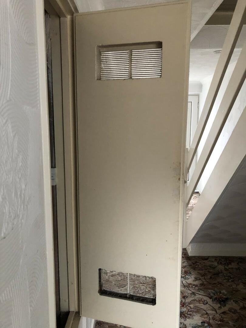 Asbestos insulating board panel on back of door of boiler cupboard in domestic property