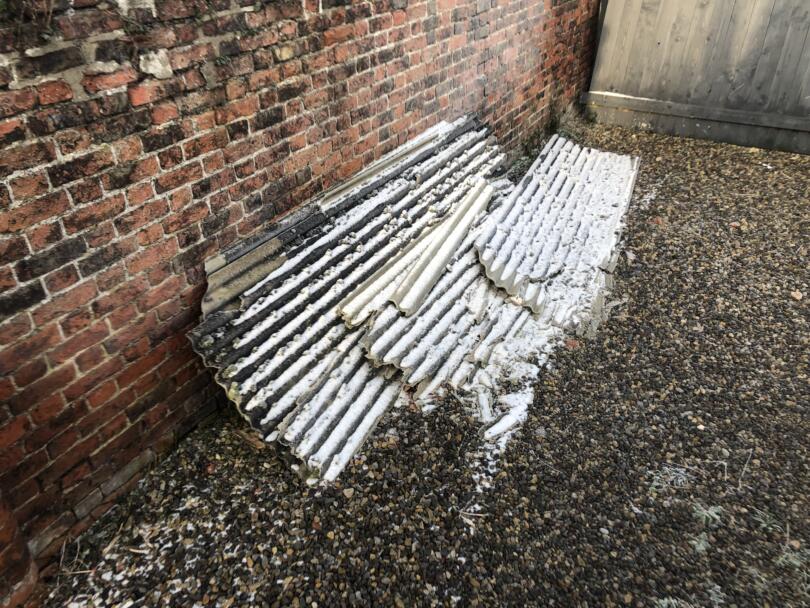 Asbestos cement damaged sheets stacked against wall