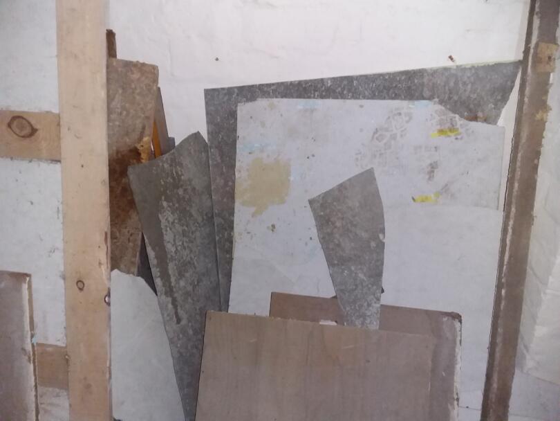 Asbestos cement sheets stacked against wall in basement of retail unit
