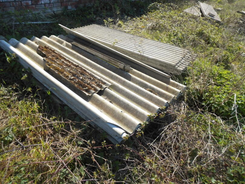 Stacked asbestos cement sheets in garden of domestic property