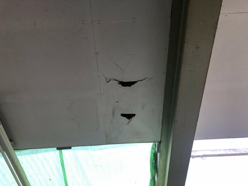 Damaged asbestos insulating board ceiling panels in commercial workshop