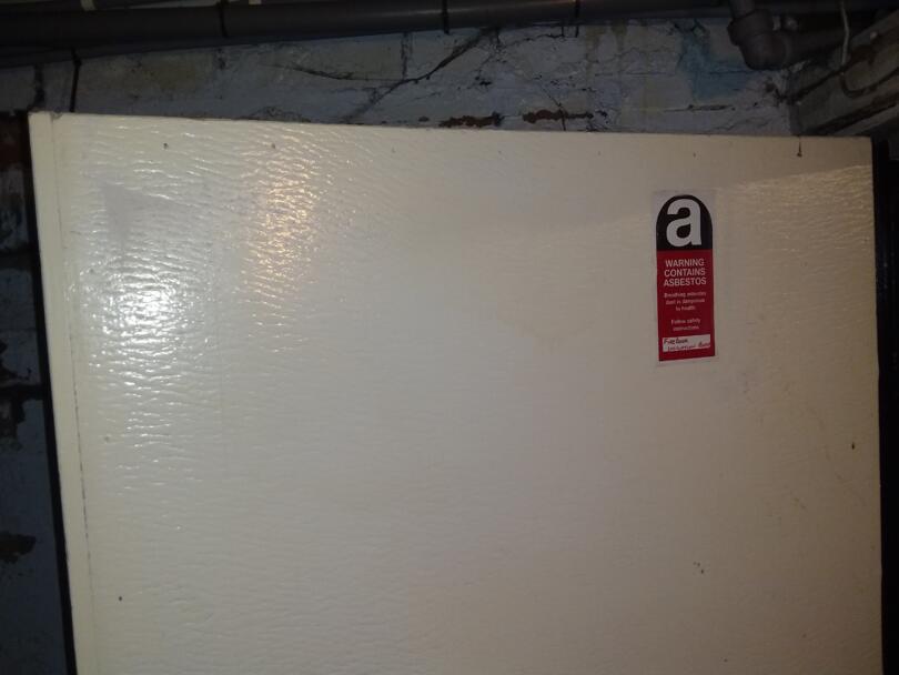 Asbestos insulating board lining to door encapsulated and labelled