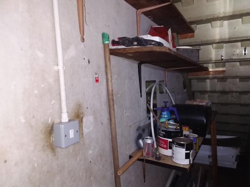 Asbestos insulating board wall panels in under stairs store room of commercial unit