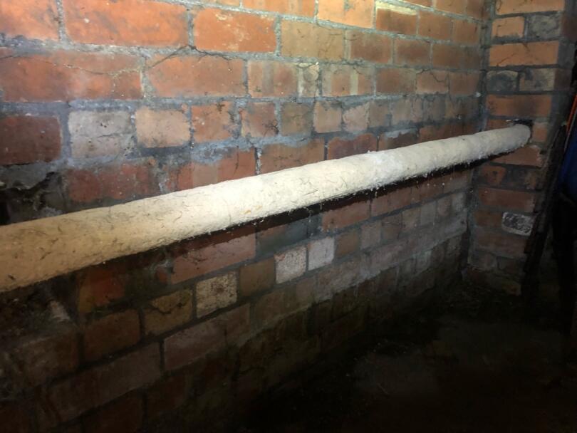 Asbestos insulation hand applied to old heating pipes under floor