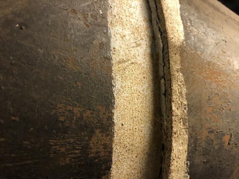 Asbestos mastic on joints of boiler flue pipe in boiler room of school