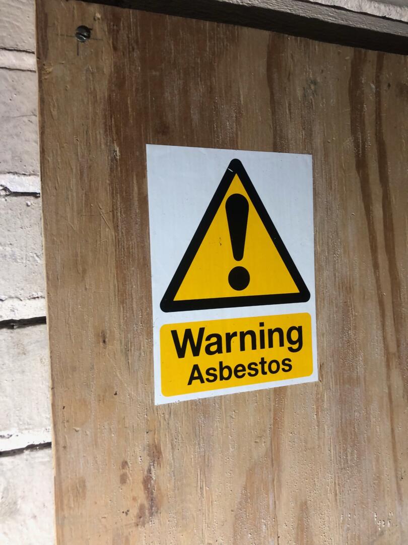 Asbestos warning sign on duct of building