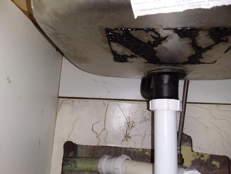 Asbestos sink pad debris on underside of sink