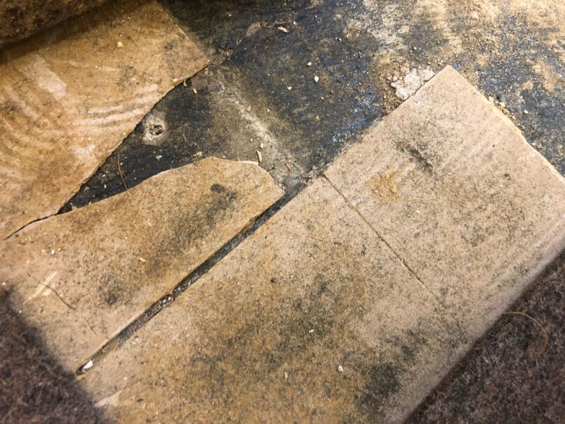 Damaged asbestos vinyl floor tiles and debris on asbestos containing adhesive