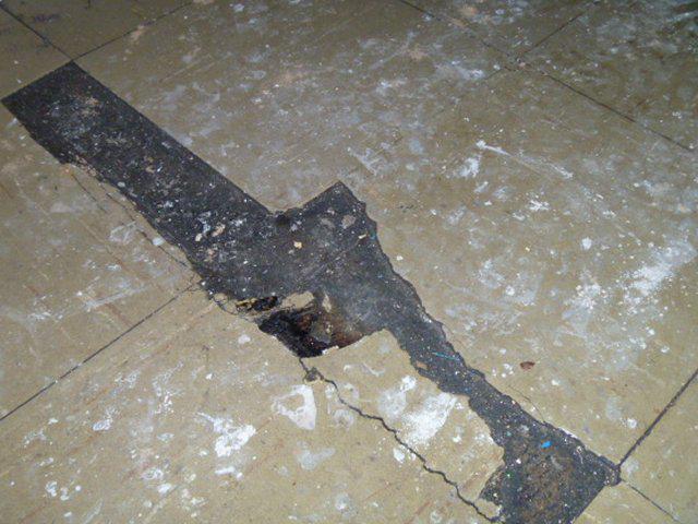 Asbestos vinyl floor tiles which are damaged and loose
