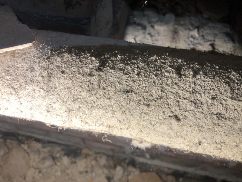 Hand applied asbestos insulation to heating pipes under church floor
