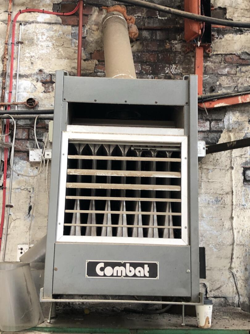 Old wall heater in industrial unit containing asbestos